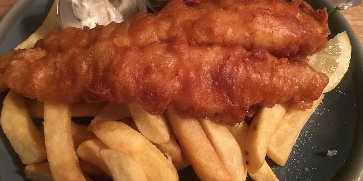 Golden battered fish and chips with lemon, tartare sauce and salad